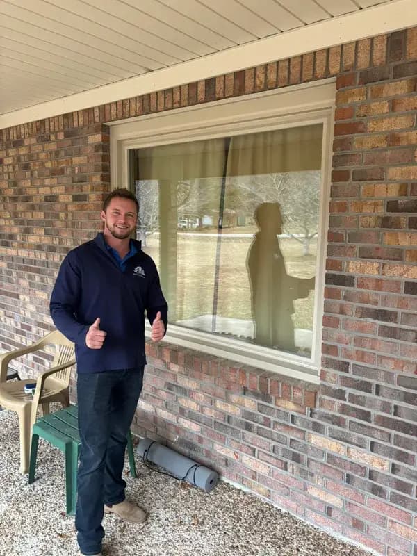An ACM team member beside a newly installed picture window on a brick ranch home